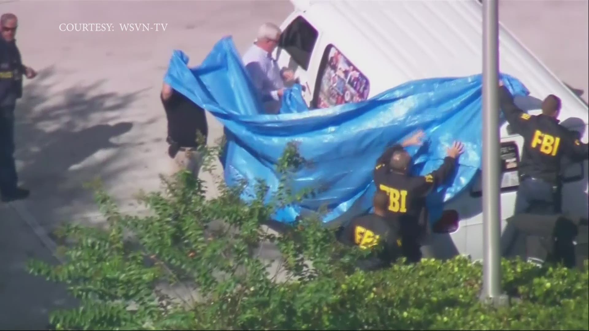 Police were seen covering a van with a blue tarp not long after two law enforcement officials say a person was taken into custody in Florida in connection with package bombs that were sent to high-profile critics of the president. (Courtesy WSVN via AP)