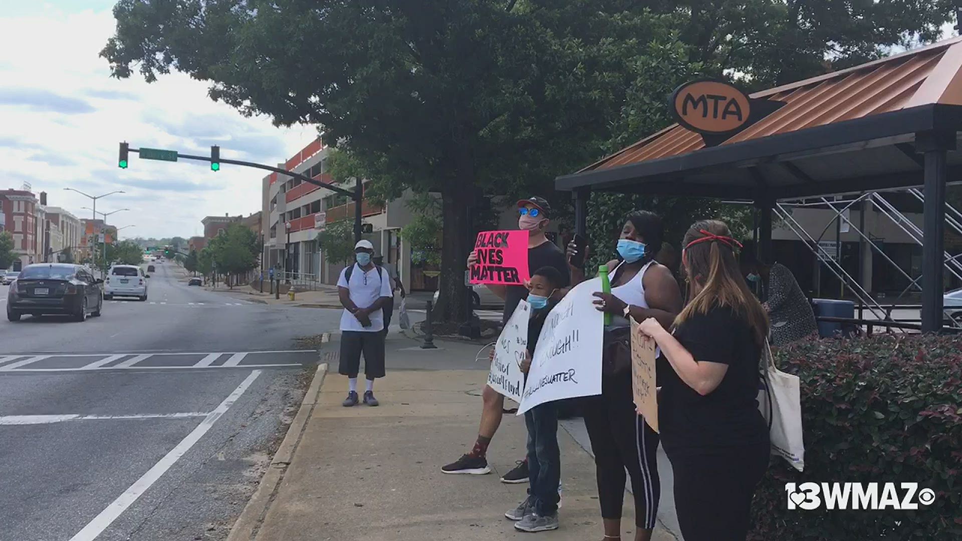 Protestors stood in front of the Douglass Theatre encouraging passing drivers to honk if they could not stand out with them.