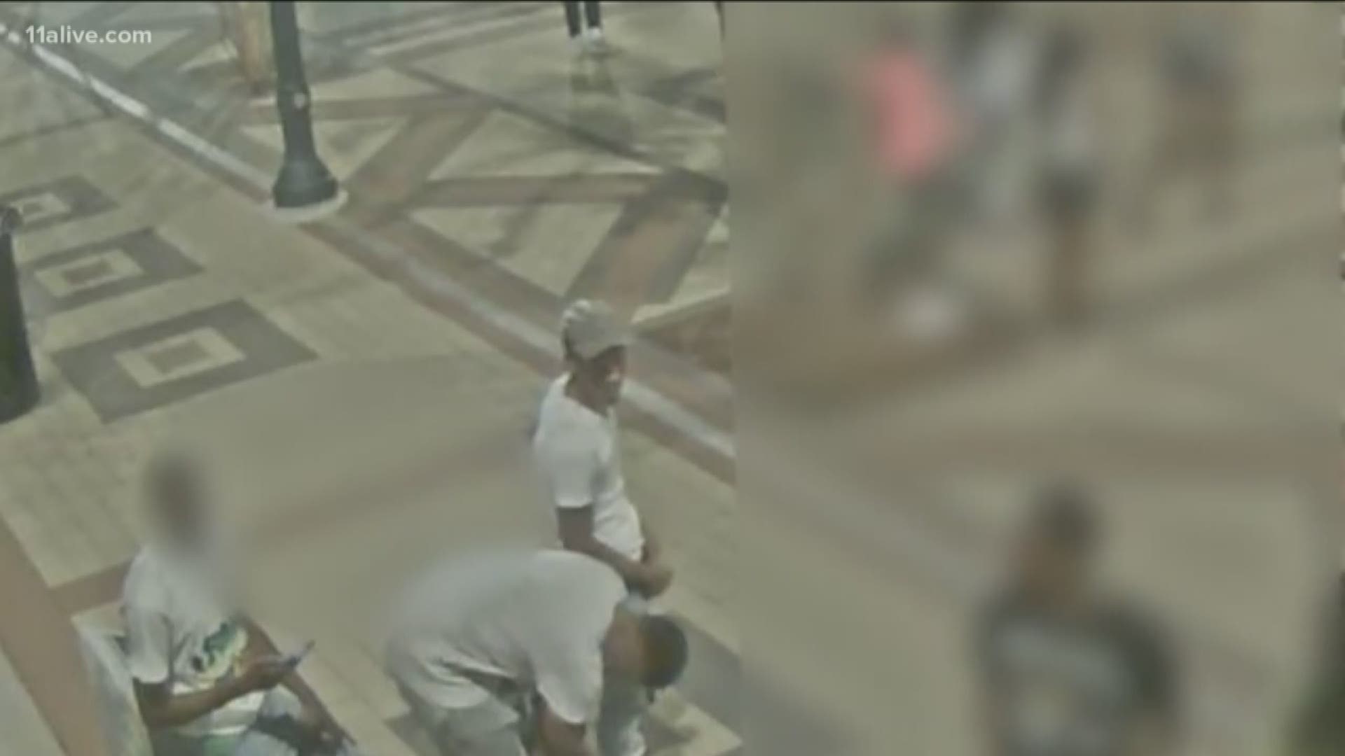 The male seen in the video is wearing a white t-shirt, gray sweat pants, a tan Gucci hat, and gray New Balance sneakers.